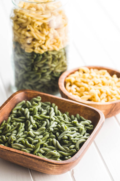 Uncooked spinach gemelli pasta in wooden bowl. - Фото, изображение