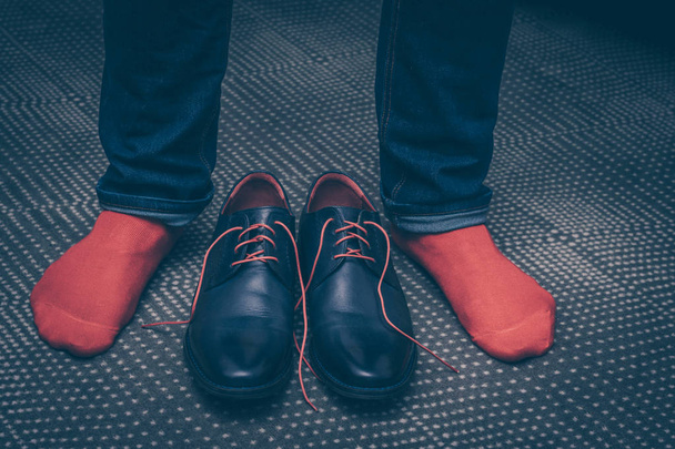 A man tries on classic leather shoes with red laces and in red stylish socks, buying shoes, a first-person view - Zdjęcie, obraz