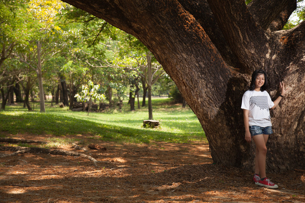 Young woman standing under a large tree. - Foto, afbeelding