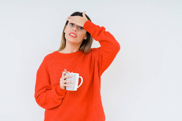 Young woman drinking cup of coffee over isolated background stressed with hand on head, shocked with shame and surprise face, angry and frustrated. Fear and upset for mistake. - Foto, Bild