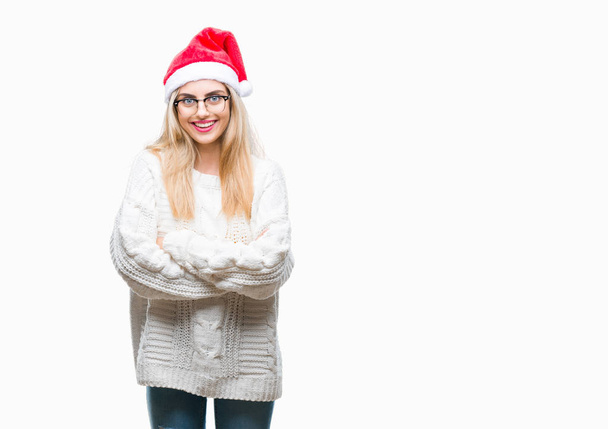 上クリスマスの帽子を着ている若い美しいブロンドの女性は、幸せそうな顔で笑顔組んだ腕のカメラを見て背景を分離しました。肯定的な人. - 写真・画像