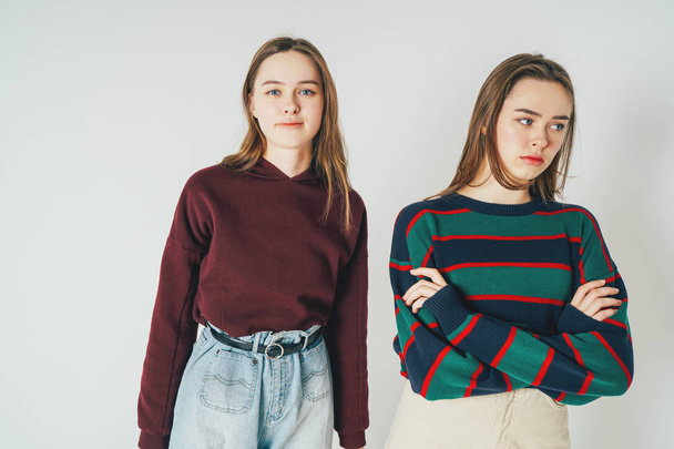 Two sisters twins beautiful girls hipsters in casual clothing antipodes smiling and sad on grey background isolated - Photo, Image