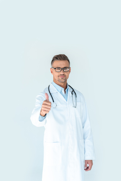 guapo doctor en gafas con estetoscopio en hombros mostrando el pulgar hacia arriba aislado en blanco
 - Foto, Imagen
