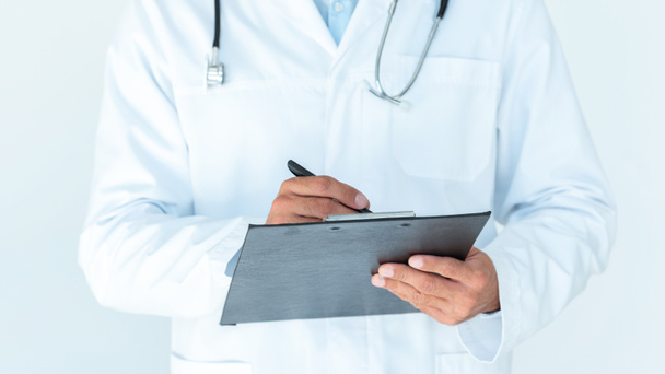 cropped image of doctor in white coat writing something in clipboard isolated on white - Foto, immagini