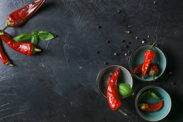 chili peppers met basilicum en peperkorrels in kommen op een rustiek oppervlak, - Foto, afbeelding