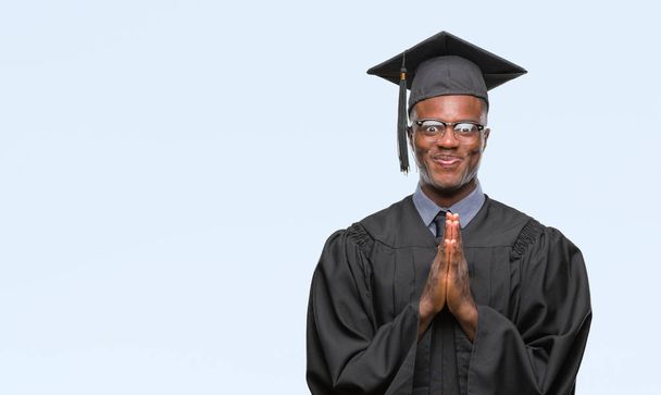 Young graduated african american man over isolated background praying with hands together asking for forgiveness smiling confident. - Photo, Image