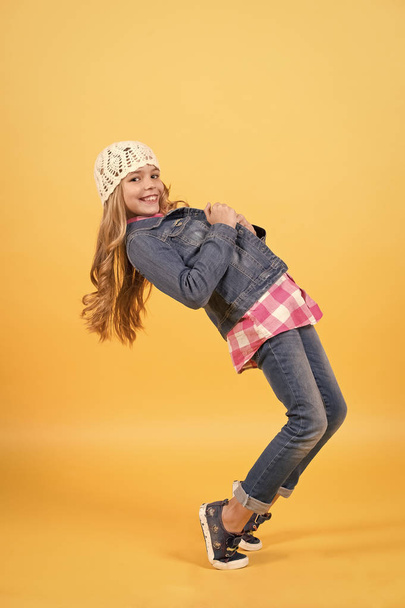 Child in jeans suit, hat, plaid shirt balance tiptoe - Фото, изображение