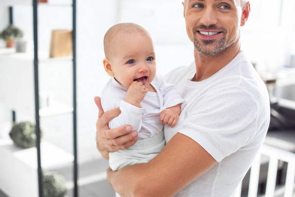 feliz padre sosteniendo alegre bebé en casa
  - Foto, imagen