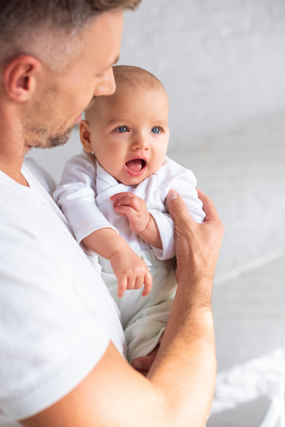 επιλεκτική εστίαση του έκπληξη το μωρό στα χέρια του πατέρα  - Φωτογραφία, εικόνα