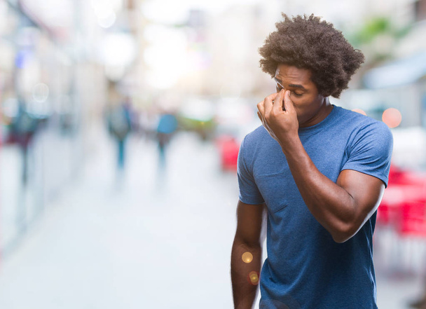 Afro-Amerikaanse man over geïsoleerde achtergrond moe wrijven neus en ogen, vermoeidheid en hoofdpijn gevoel. Stress en frustratie concept. - Foto, afbeelding