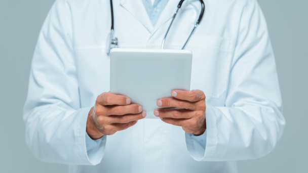 обрезанное изображение врача со стетоскопом, держащим таблетку, изолированную на белом
 - Фото, изображение