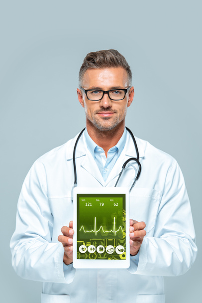 guapo doctor con estetoscopio mostrando tableta con aparato médico aislado en blanco
 - Foto, Imagen