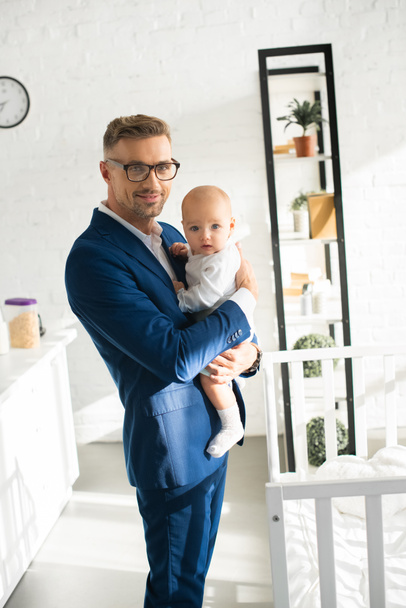 handsome businessman holding infant daughter in room  - Foto, Imagen