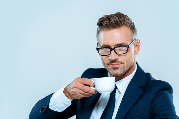 handsome businessman drinking coffee and looking at camera isolated on white - Foto, imagen