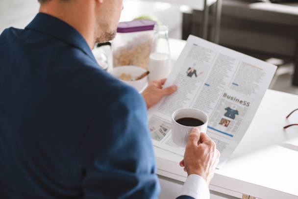 abgeschnittene Ansicht von Geschäftsmann, der Wirtschaftszeitung liest und Tasse mit Kaffee hält - Foto, Bild