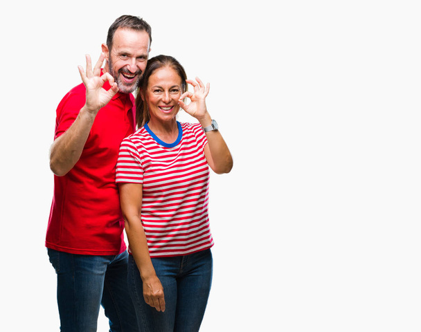 Średnim wieku hiszpanin para zakochanych na na białym tle tło uśmiechający się pozytywne, robi ok znak z dłoni i palców. Pomyślne wyrażenie. - Zdjęcie, obraz
