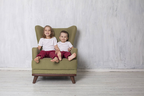 μικρό αγόρι και κορίτσι είναι αδελφός και αδελφή καθίσει σε μια καρέκλα Πράσινη - Φωτογραφία, εικόνα