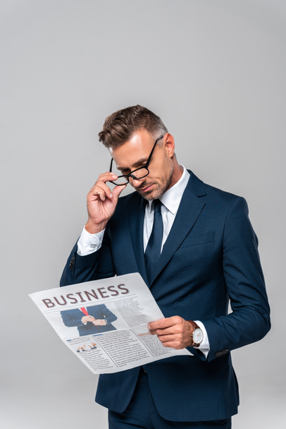 handsome businessman touching glasses and reading newspaper isolated on white - Φωτογραφία, εικόνα