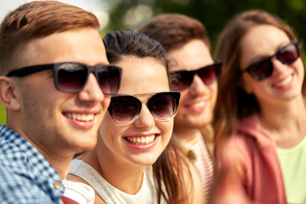 happy teenage friends in sunglasses outdoors - Fotó, kép