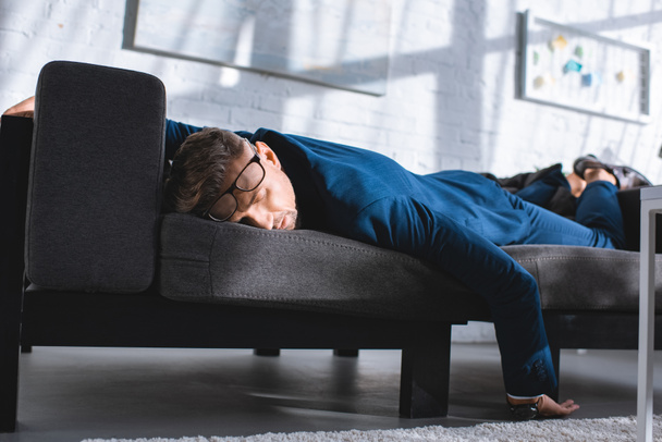 drunk businessman sleeping on sofa in glasses - Foto, afbeelding