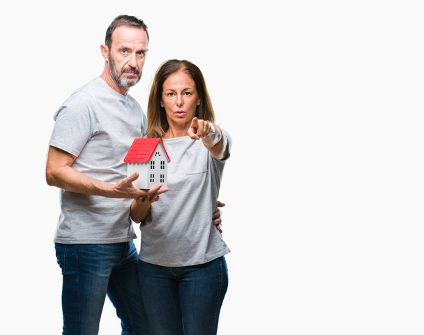 Middle age hispanic casual couple buying new house over isolated background pointing with finger to the camera and to you, hand sign, positive and confident gesture from the front - Fotoğraf, Görsel