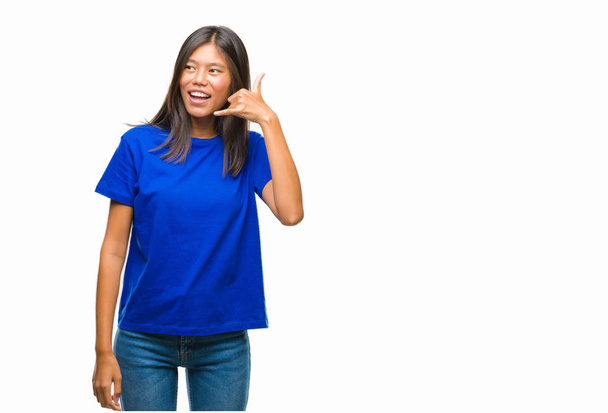 Jonge Aziatische vrouw over geïsoleerde achtergrond doen glimlachen telefoon gebaar met hand en vingers als praten aan de telefoon. Concepten communiceren. - Foto, afbeelding