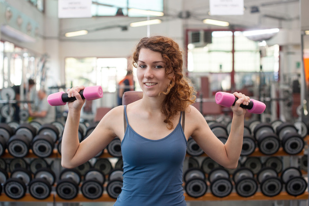 Young woman exercising with dumbbells in the gym. - 写真・画像
