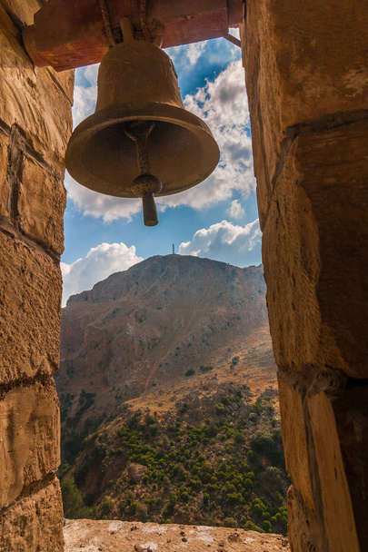 Una campana de capilla por cueva de Agia Sofia en un paisaje montañoso salvaje en la isla de Creta, Grecia, Europa
. - Foto, imagen