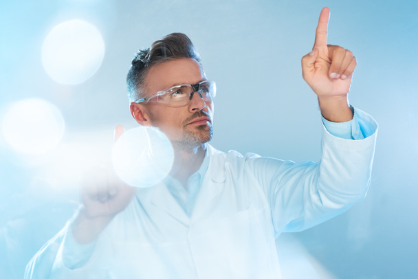 handsome technologist in protective glasses and white coat touching something isolated on white, artificial intelligence concept - Photo, Image