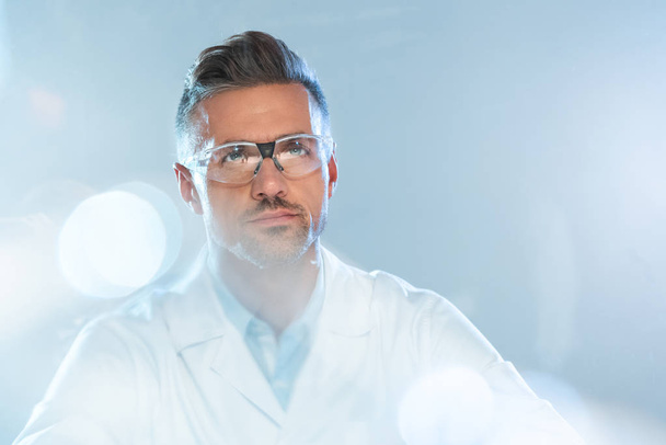 retrato de guapo científico en gafas protectoras mirando hacia arriba aislado en blanco, concepto de inteligencia artificial
 - Foto, imagen