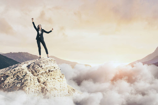 Щаслива бізнес-леді на скелі з хмарами і копіювати простір. Концепція святкування та перемоги
  - Фото, зображення