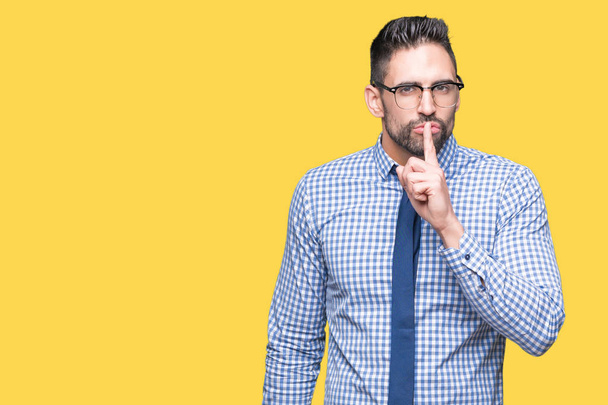 Молодий бізнесмен носить окуляри над ізольованим тлом з проханням бути тихим пальцем на губах. Тиша і таємна концепція
. - Фото, зображення