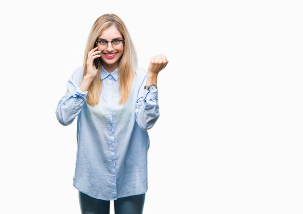 Young beautiful blonde business woman calling on smartphone over isolated background screaming proud and celebrating victory and success very excited, cheering emotion - 写真・画像