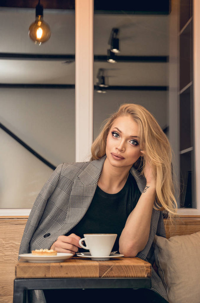 Beautiful young blonde woman with a cup of coffee in a cafe - Foto, immagini