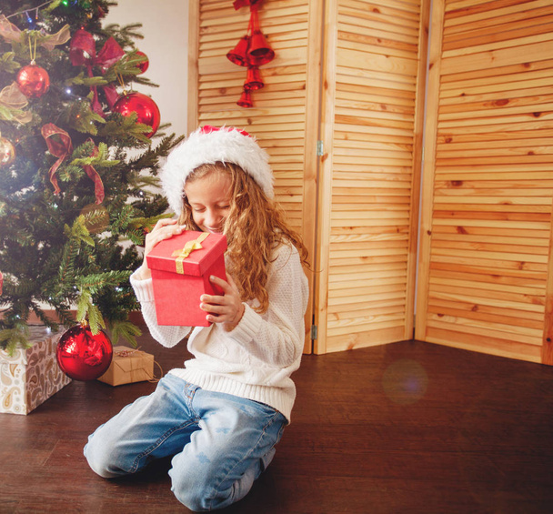 Child with gift near christmas tree - 写真・画像