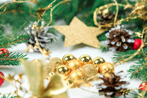 New Year's background. Christmas jewelry on fir-tree branches, gold spheres, garlands, a big gold star of an ishishka on branches. White background - Photo, image