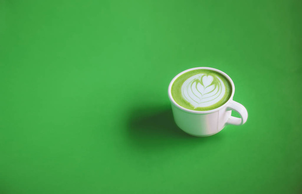 Green tea concept, Hot matcha green tea milk cream with art on top with white cup on green background for banner design with copy space. View from above. - Foto, immagini