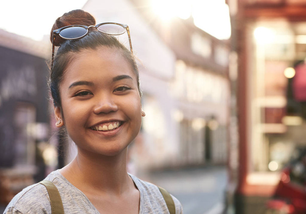 Close up image of a casually dressed young beautiful Asian woman smiling while spending an afternoon walking around the city - Foto, afbeelding