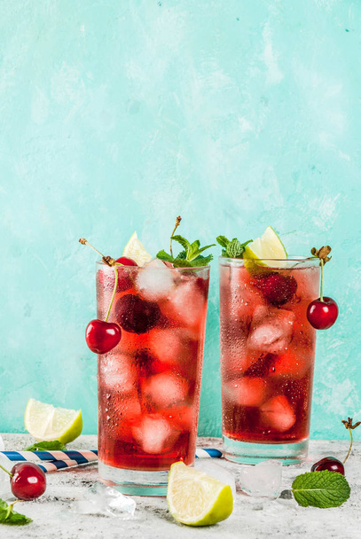 Zomer iced verfrissing drankje, cherry cola limonade of mojito cocktail in hoog glas, op lichte blauwe en grijze achtergrond kopie ruimte - Foto, afbeelding