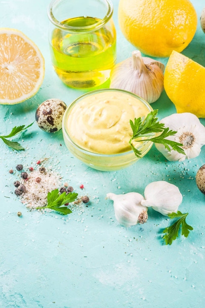 Homemade mayonnaise sauce with ingredients - lemon, eggs, olive oil, spices and herbs, light blue background copy space - Photo, Image