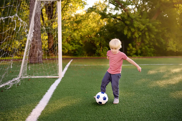 Little boy having fun playing a soccer/football game on summer day. Active outdoors game/sport for children. Kids soccer classes and camps - Φωτογραφία, εικόνα