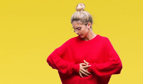 Young beautiful blonde woman wearing red sweater and glasses over isolated background with hand on stomach because indigestion, painful illness feeling unwell. Ache concept. - Photo, Image
