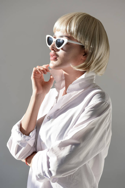 attractive blonde woman in sunglasses and stylish white outfit looking away isolated on white - Foto, immagini