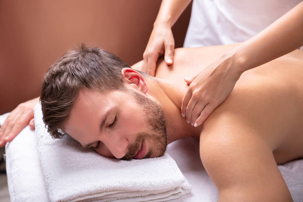Close-up Of A Relaxed Young Man Receiving Shoulder Massage - Фото, изображение