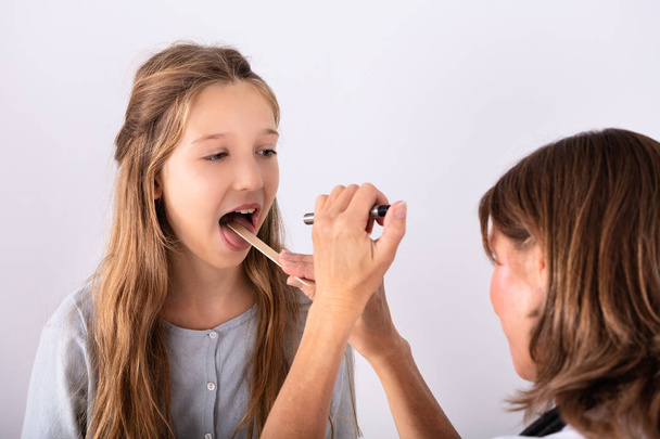 Close-up Of Doctor Checking Girl's Sore Throat With Tongue Depressor - Foto, afbeelding