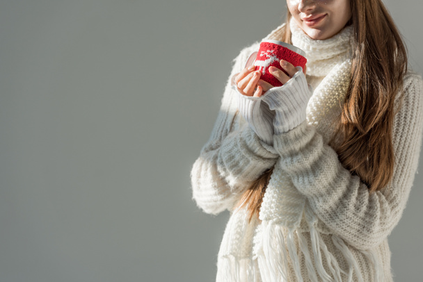 cropped image of woman in fashionable winter sweater and scarf holding cup of tea isolated on grey - Фото, изображение