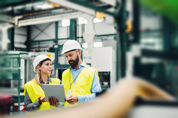 A portrait of an industrial man and woman engineer with tablet in a factory. - Foto, Bild