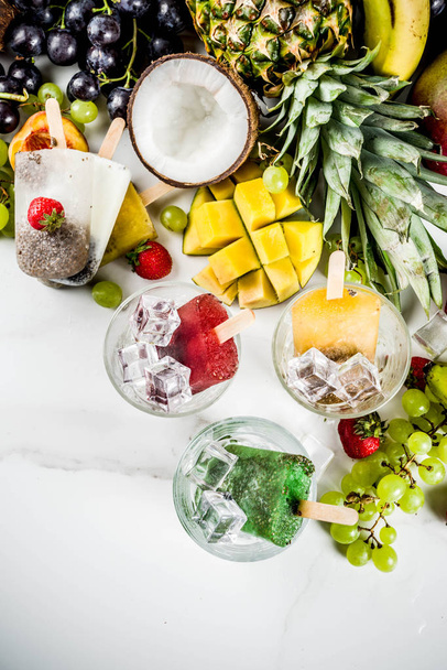 Tropical ice cream popsicles with chia seeds and fruit juices - pineapple, orange, mango, banana, kiwi, coconut, grapes, peach, strawberry, copy space - Foto, Bild