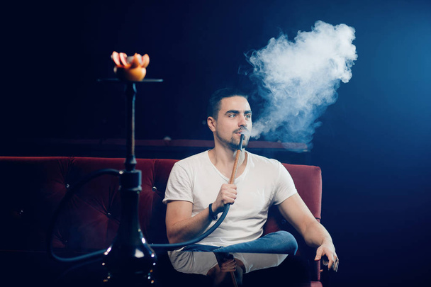 Ο νεαρός άντρας κάπνισμα ναργιλέ μόνος στο shisha lounge bar κινηματογράφηση σε πρώτο πλάνο - Φωτογραφία, εικόνα
