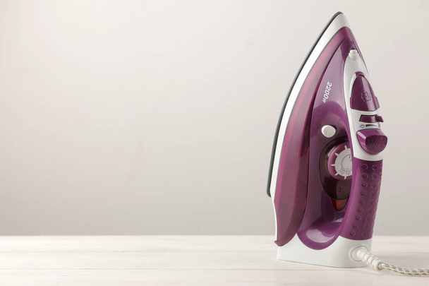 lilac iron on a light background. ironing clothes. household electrical appliances. - Photo, Image